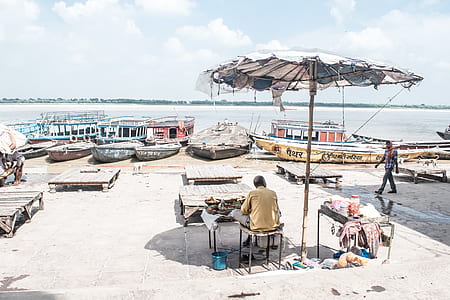 man sitting on chair near on bay near body of water thumbnail