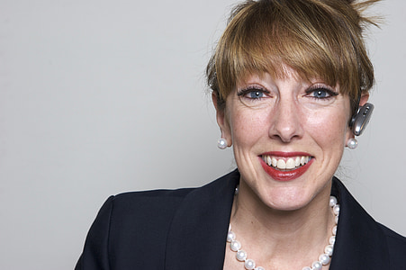 portrait photo of woman wearing black suit and Bluetooth earpiece thumbnail