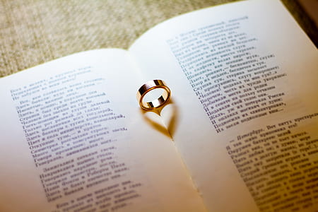 gold-colored wedding band on white book page thumbnail