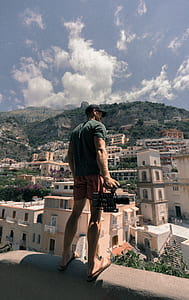 man stainding and holding camera thumbnail