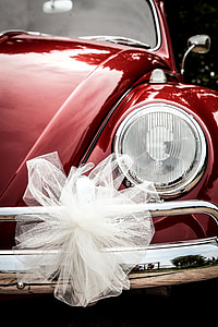 closeup photo of white bow on red Volkswagen Beetle headlight thumbnail