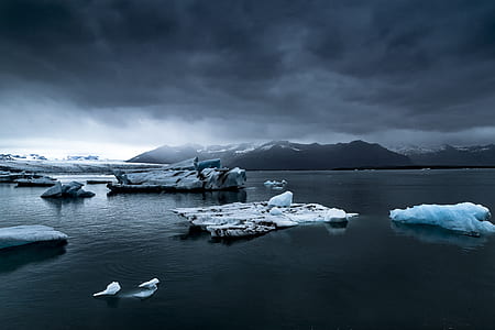 iceberg on body of water beside mountain field of snow thumbnail