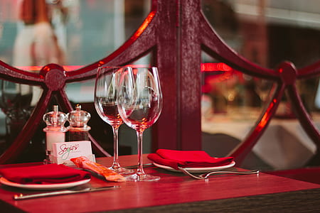 two clear wine glasses placed on red wooden table thumbnail