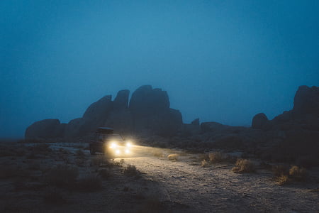 turned-on vehicle lights on road near mountains during nighttime thumbnail