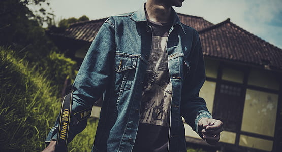 person in blue denim button-up shirt carrying black Nikon camera thumbnail
