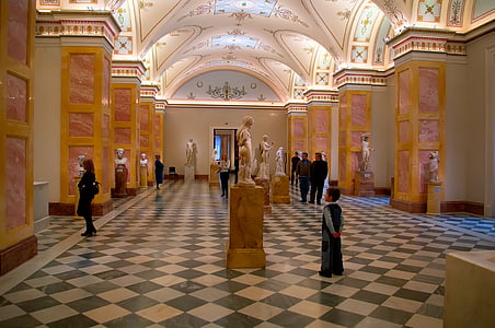 people standing and walking inside museum with statuettes thumbnail