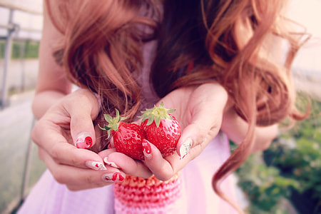 selective focus photography of a woman holding two strawberries thumbnail