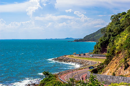 brown concrete road beside beach during daytime thumbnail