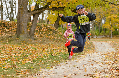 group of children running and jumping near trees during daytime thumbnail