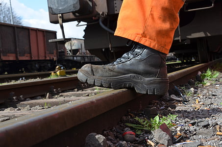 person wearing black leather combat boot stepping on train track thumbnail
