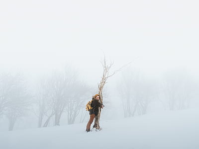 man hugging tree in the middle of snow field thumbnail