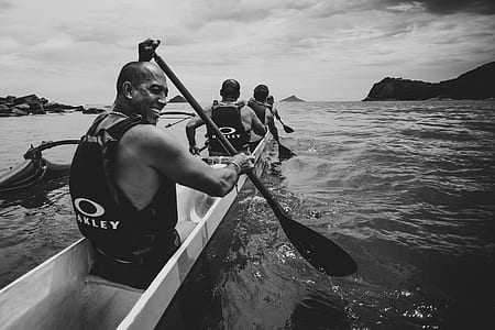 grayscale photo of men paddling boat thumbnail