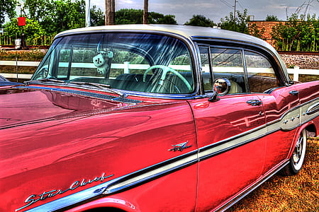 red sedan parked near white fence during daytime thumbnail