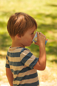boy drinking from cyan cup selective focal photo thumbnail
