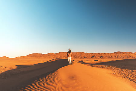 man walking on desert under blue sky thumbnail