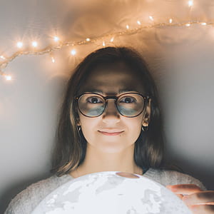 woman smiling beside string lights thumbnail