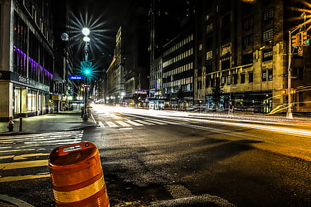 streetlights turned on roadside near concrete buildings thumbnail