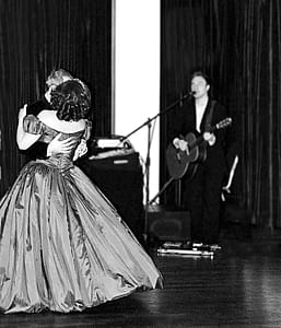 grayscale photo of man playing guitar while singing and man dancing with woman on floor thumbnail