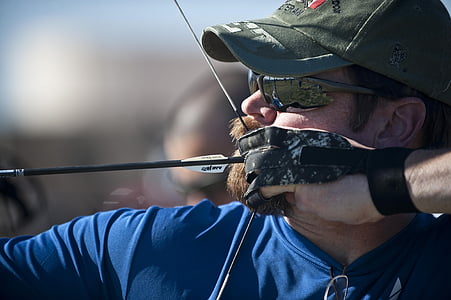 man wearing green fitted cap holding black and white bow thumbnail