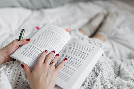 Soft photo of woman on the bed with the book and cup of coffee in hands thumbnail
