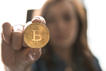 selective photography of person holding gold-colored coin thumbnail