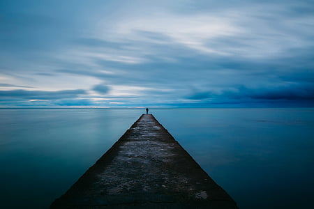 man standing at the edge of breakwater bridge thumbnail