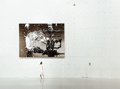 standing woman looking down in front of painting on wall thumbnail