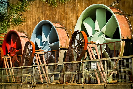 three red, blue, and green windmills near brown wooden wall thumbnail