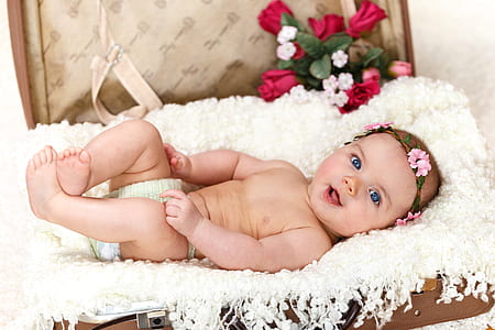 baby lying on white pad with floral crown headpiece thumbnail