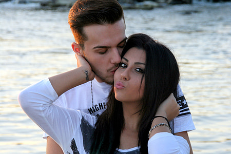 man kissing woman standing near body of water thumbnail