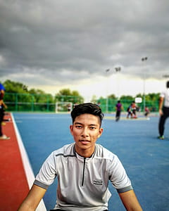 Tilt Lens Photography of Man Sitting Near Soccer Field during Cloudy Day thumbnail