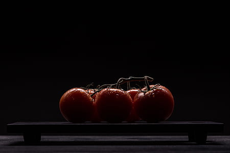five red tomato fruits on black table thumbnail