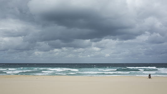 person riding on motorcycle near seashore under grey cloudy sky thumbnail