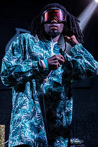 man with brown dreadlock hair in blue and white zip-up jacket wearing red goggles thumbnail
