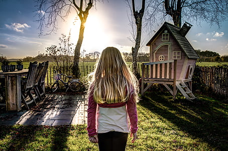 girl standing near wooden playhouse thumbnail