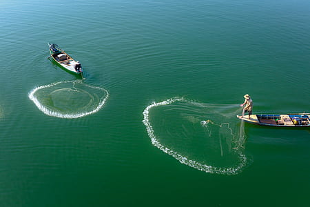 two boats on body of water throwing fish net thumbnail