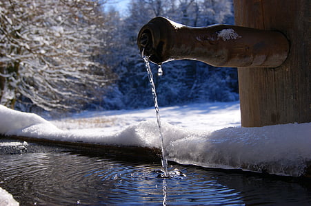 brown bamboo faucet dropping water near trees covered with snow at winter thumbnail