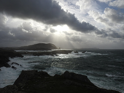 ocean waves crushing on rock formation under gray heavy clouds photography thumbnail