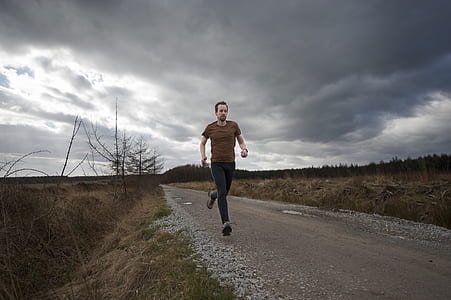 man running between hay field under cloudy sky during daytime thumbnail