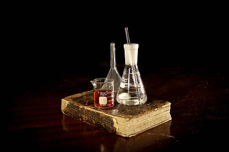 three assorted measuring bottles on brown hardbound book thumbnail