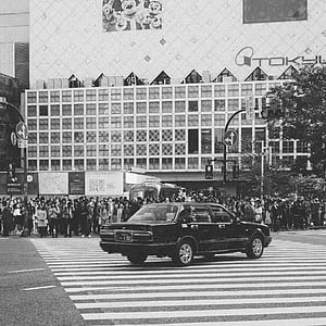 gray scale photo of sedan crossing the pedestrian lane thumbnail