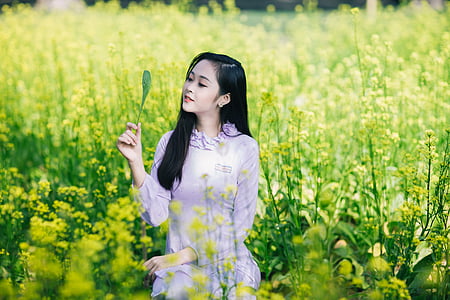 woman holding green leaf on green flower field thumbnail