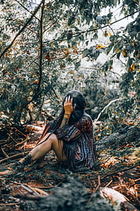 woman in black top sitting beside tree thumbnail