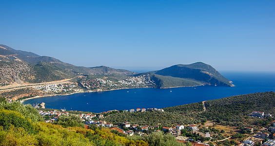 green island besides body of water under blue sky at daytime thumbnail