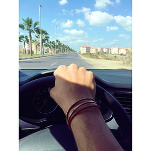 Person Withe Bracelets Holding Black Steering Wheel thumbnail