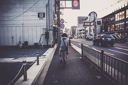 person ride on bike beside black steel fence thumbnail
