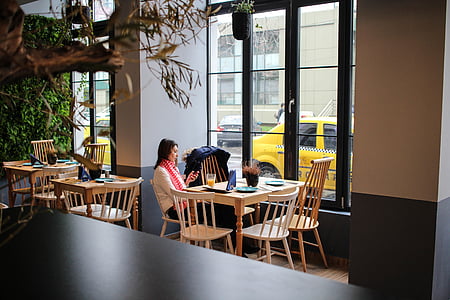 woman all alone sitting by table near window during daytime thumbnail