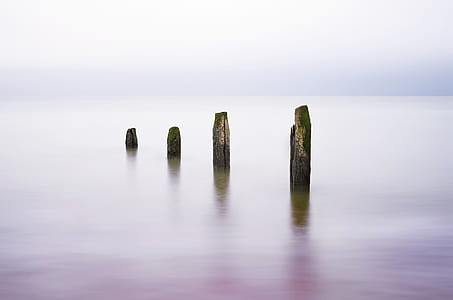four grey rocks on blue body of waters at daytime thumbnail
