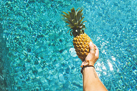 A man holding pineapple fruit over water thumbnail