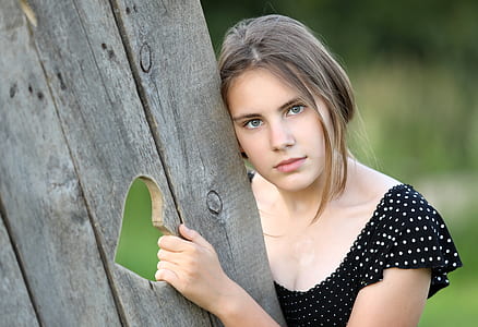 woman wearing black and white polka-dot top holding grey wooden heart cut out board thumbnail